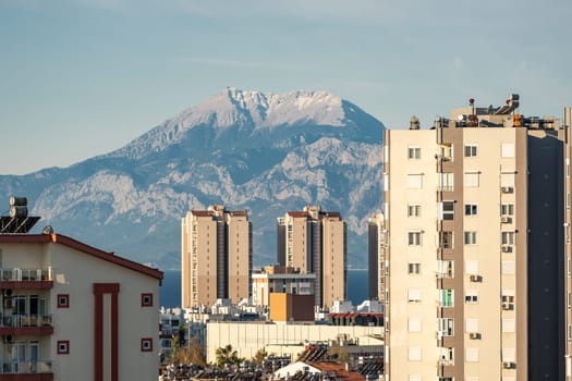 Snowy mountain peak visible through city buildings on a sunny day