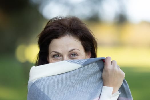 A woman is wearing a scarf and is hiding her face. The scarf is white and gray