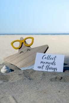 COLLECT MOMENTS NOT THINGS text on paper greeting card on background of funny starfish in glasses summer vacation decor. Sandy beach sun coast. Slowing-down, enjoying the moment, good moments, slow life Holiday concept postcard. Getting away Travel Business concept