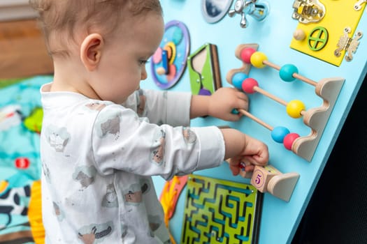 Baby girl playing with a wooden set of entertaining board game elements.
