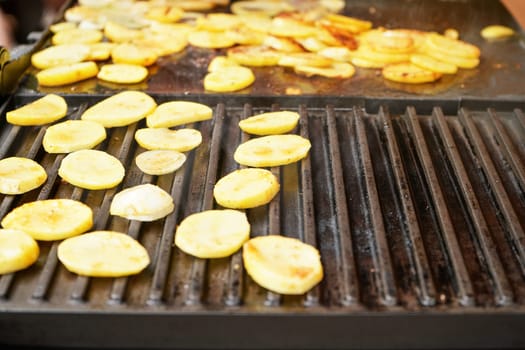 Potatoes cut into small chips grilled on electric grill, closeup detail