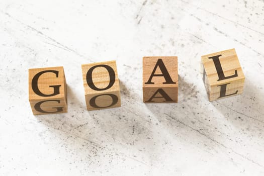 Four wooden cubes with word GOAL on white working board.