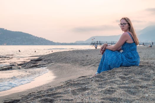 Woman sits on the beach and looks at the sea in Alanya city, Turkey. Travelling or vacation concept