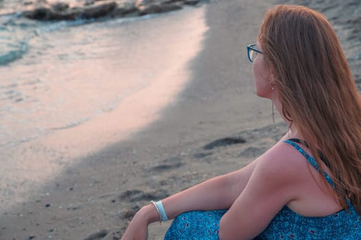 Woman sits on the beach and looks at the sea in Alanya city, Turkey. Travelling or vacation concept