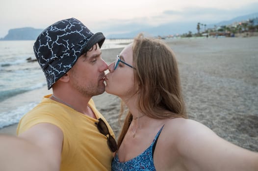 Happy couple taking a photo on a beach at the sea in Alanya city, Turkey. Travelling or vacation concept