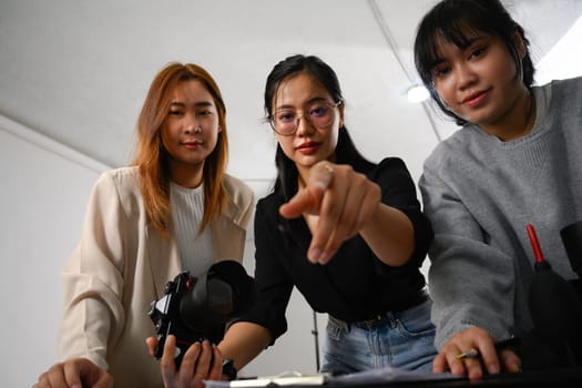 Group of young creative people working together in studio during photo session.