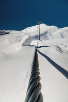 Steel cable of a cable car close-up. Rope texture. The path of the cable cabin against the backdrop of snow-capped mountains.