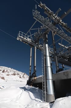 A cable car station high in the mountains under construction. Snowy mountain landscape and construction of a metal structure for a cable car.