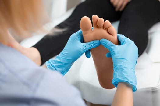 Close up of masseur doing foot reflexology massage to woman at beauty salon.
