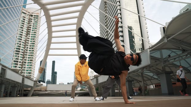 Group of professional street dancer cheer up while asian hipster perform freestyle footstep at city surrounded by people with low angle camera. Break dance concept. Outdoor sport 2024. Sprightly.