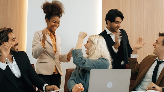 Diverse group of office worker and employee raise their hands up with happy and excited celebration for being good teamwork and positive attitude contribute to business success in ornamented workplace