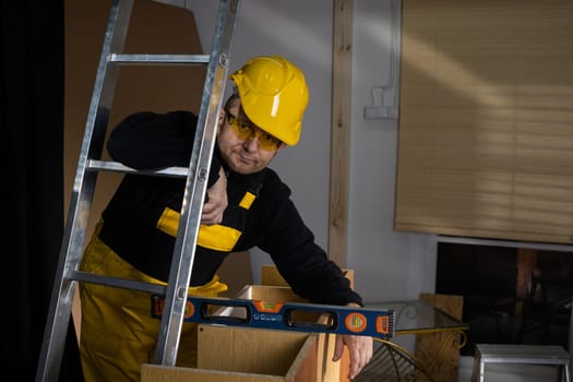 After completing the cabinet frame, the employee checks the accuracy of the vertical and horizontal with a spirit level. An employee wearing personal protective equipment.