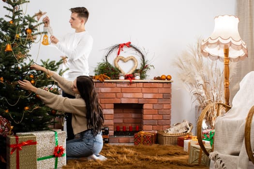 The tired fiancee sits on the floor and shows her fianc where to hang the next Christmas tree decoration. Christmas.