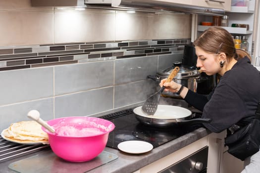 The girl checks if the pancake is ready to be turned over. Tasty homemade pancakes from a young woman's hand.