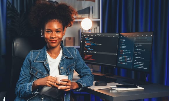 Young African wearing jeans shirt, IT developer presenting program on computer screens displaying coded data of application and website, creating innovative updated software version. Tastemaker.