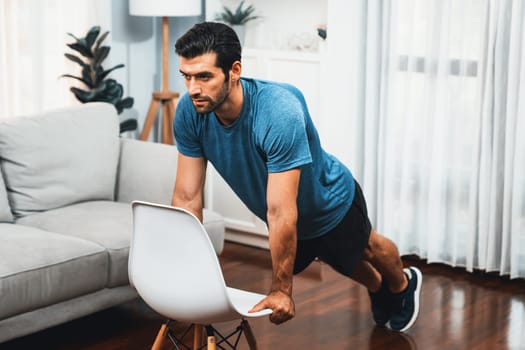 Athletic body and active sporty man using furniture for effective targeting muscle gain exercise at gaiety home exercise as concept of healthy fit body home workout lifestyle.