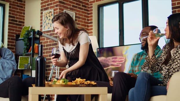 Woman telling entertaining story to apartment party guests during weekend gathering, gossiping about annoying friend. Group of people listening to funny tale from host while drinking wine