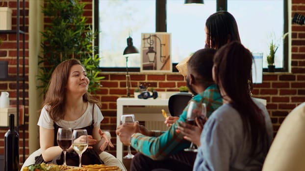 Multiracial mates invited to birthday party offering presents to asian woman. Guests surprising their friend with neatly packaged present in her apartment, drinking wine and socializing
