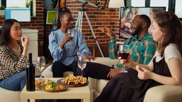 African american, asian and caucasian employees celebrating business success at work, gathered at home to toast wine drinks for their accomplishments, throwing house party in modern living room