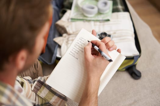 Close up portrait of man going through check-list, packing for holiday, looking at items he wants to bring on vacation.