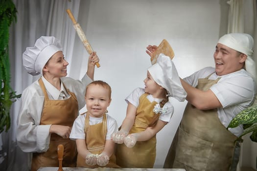 Cute oriental family with mother, father, daughter, son cooking in kitchen on Ramadan, Kurban-Bairam, Eid al-Adha. Funny fighting parents at cook photo shoot. Pancakes, pastries, Maslenitsa, Easter