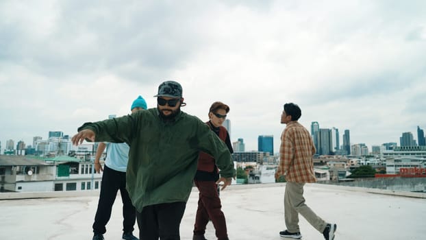 Professional break dance team practice B-boy dance while multicultural friends at rooftop. Young modern dancing group doing hip hop movement. Style,fashion,action. Outdoor sport 2024. Endeavor.