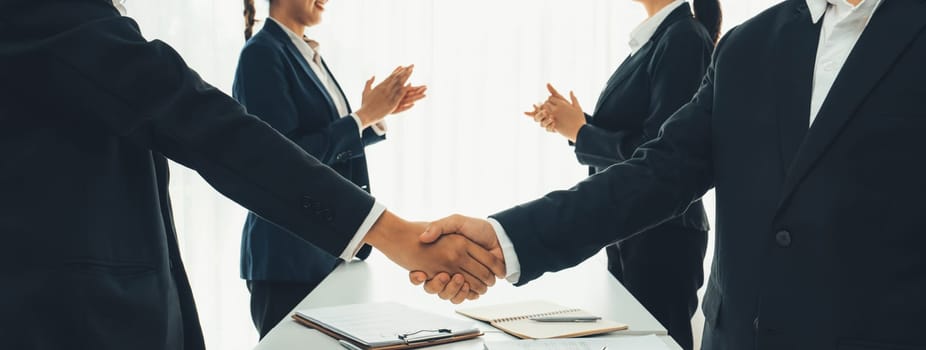 Two business executive shake hand in boardroom, sealing agreement merging two company. Handshake symbolize business partnership and cooperation. Corporate acquisition and merger concept. Shrewd