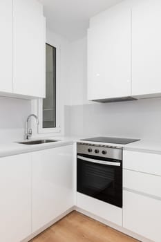 Modern white kitchen with sleek cabinets and a stylish black stove top oven.