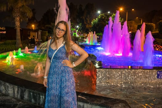 Woman on light and colour fountain background in night city Alanya, Turkey in 2023.