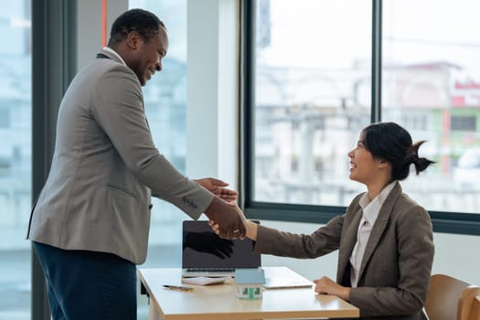 Real estate broker agent manager shaking hands with a client after successful agreement in the office..