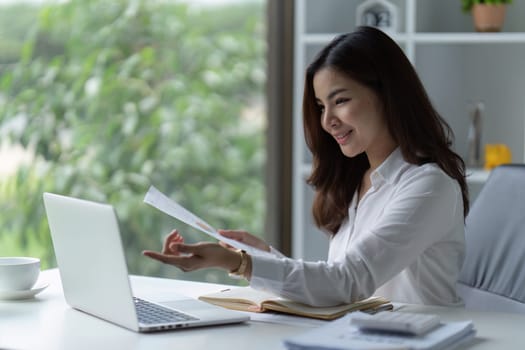 Asian Businesswoman sitting at her desk and busy working on a laptop in office.