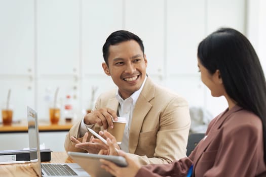 Businessman manager explaining and coaching Asian colleague financial project on laptop.