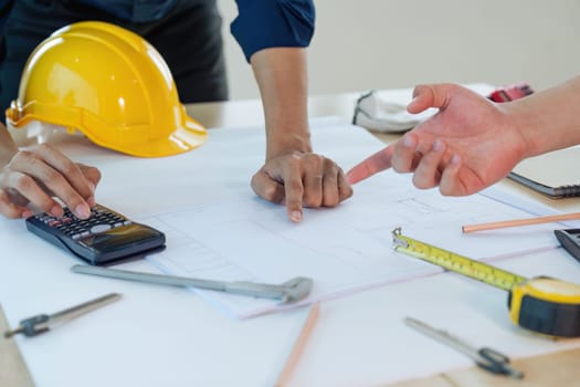 Close up of civil male engineer asian working on blueprint architectural project at construction site at desk in office.