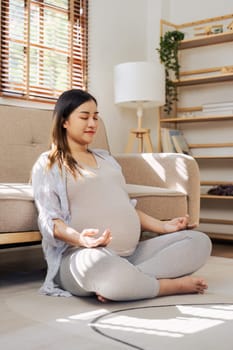 Healthy Pregnancy Yoga and Fitness. Young pregnant yoga woman and meditation in living room.