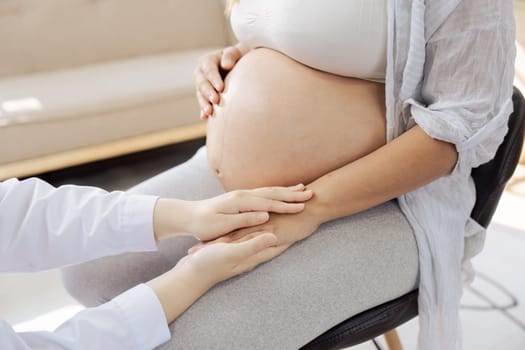 Doctor touching a pregnant woman belly, feeling the baby inside the tummy..