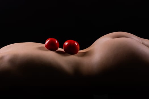 Nude woman with a red apple on her back, dark background