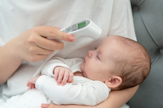 Mother carefully measuring the temperature of her infant baby with a precise electronic thermometer