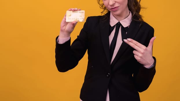 beautiful young business woman standing isolated over yellow background, holding credit card