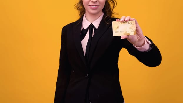 business woman standing isolated over yellow background, holding credit card