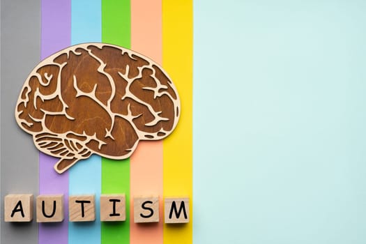 Mock up of the human brain on a colorful background. Six cubes with the inscription autism.