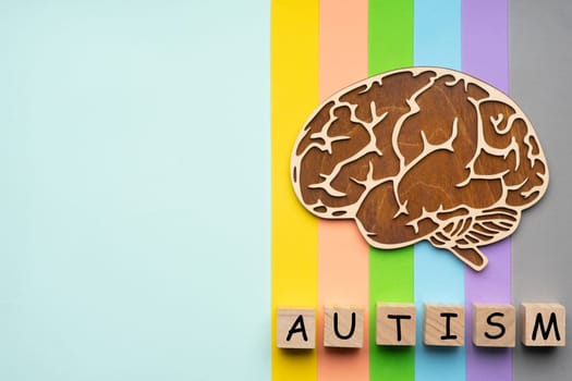 Mock up of the human brain on a colorful background. Six cubes with the inscription autism.