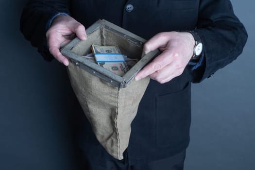 Man's hands holding a bank bag full of money.