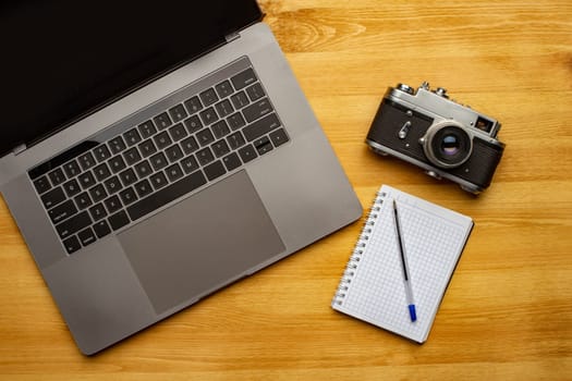 Top view off office photography desk table with laptop, notebook, camera and pen.