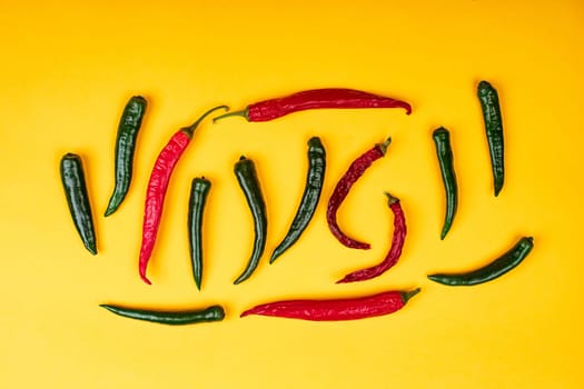 Red and green hot chili peppers on yellow background