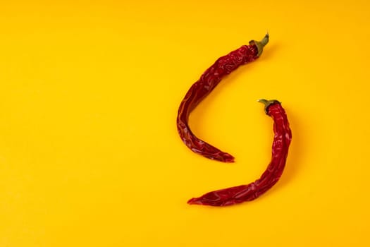 Red dry hot chili peppers on yellow background.