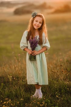 a little girl in a light green dress with a bouquet of lavender in a field at sunset.