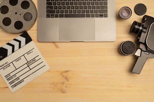 Movie clapper, laptop and camera on wooden background, top view