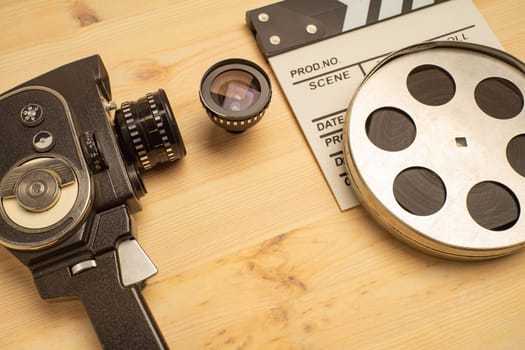 Movie clapper, film reel and camera on wooden background, top view