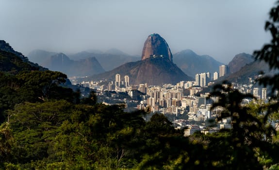 View of Sugarloaf Mountain and Urca Hill above Rio de Janeiro's cityscape, with empty sky for copy space.