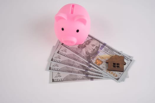 Toy house and pig piggy bank on american dollar bills on white background.